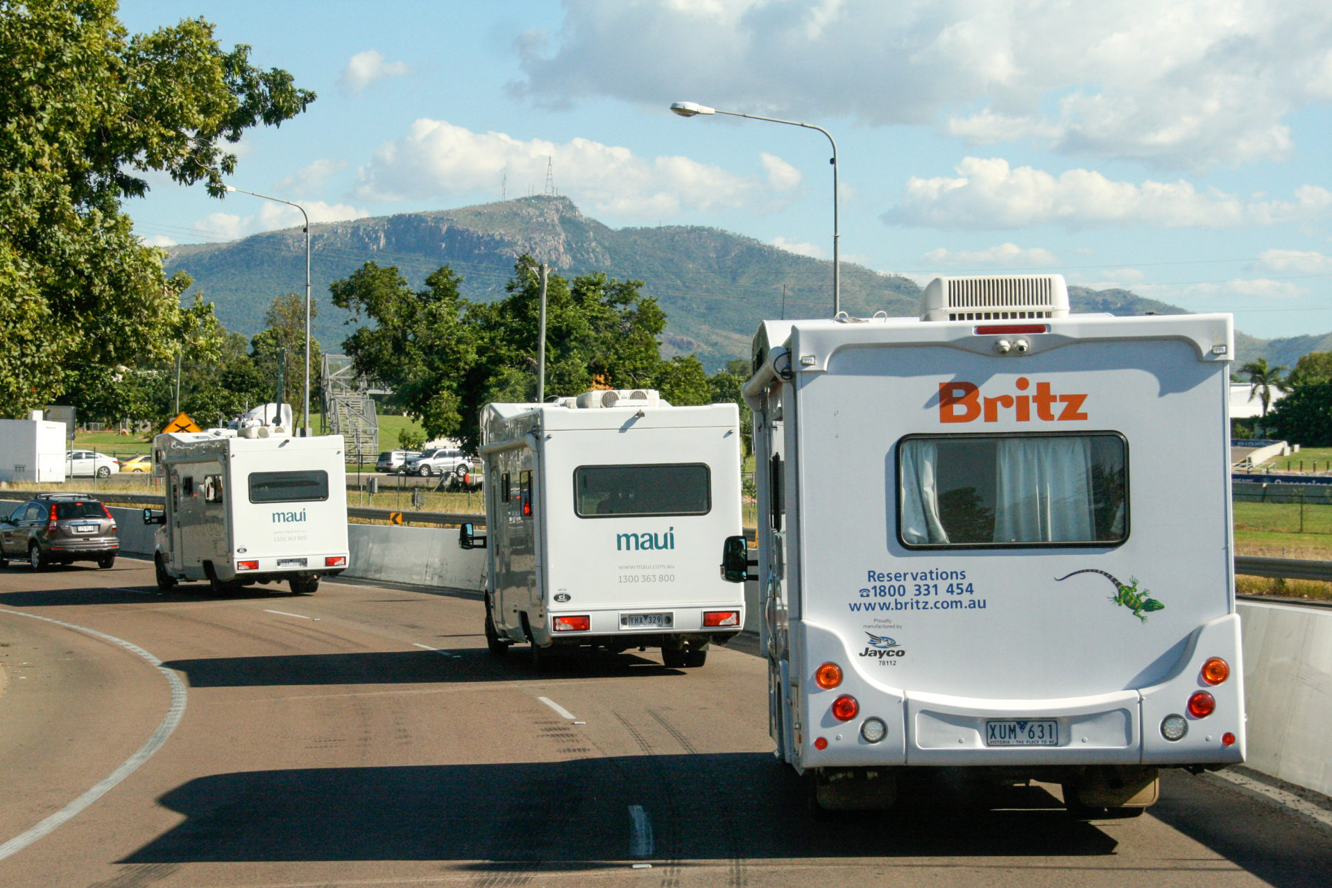 Kolonne von Wohnmobilen an der Küste von Queensland mit Bergen im Hintergrund